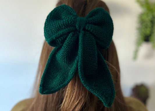 Green knitted hair bow on a person's head with a blurred background